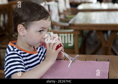 Das Kind trinkt Saft am Tisch im Café Stockfoto