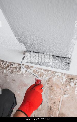 Malerhand trägt die Farbe mit einer Walze vertikal auf den auf Wand Stockfoto