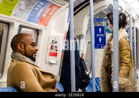 London, Großbritannien. Januar 2021. Ein Mann scheint entspannt zu sein, keine Maske zu tragen, trotz der Schilder über ihm und dem Aussehen anderer maskierter Passagiere - die U-Bahn ist trotz der neuen nationalen Sperre, Aufenthalt zu Hause, Anweisungen immer noch ziemlich voll. Die meisten Reisenden tragen Masken, da sie bereits obligatorisch sind. Kredit: Guy Bell/Alamy Live Nachrichten Stockfoto