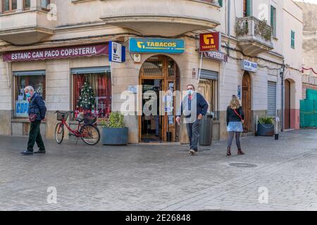 Llucmajor, Spanien; dezember 17 2020: Urbane Szene einer Person, die geht und Leute, die Schlange stehen, um einen Tabakladen zu betreten. Neuer Normalwert Stockfoto