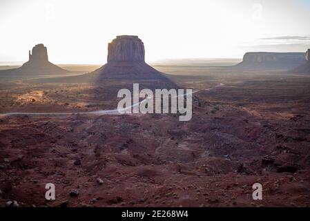 Die East Mitten und Merrick Butte Felsformationen und Straße bei Sonnenaufgang im Monument Valley Navajo Tribal Park auf der Arizona und Utah State Line, USA Stockfoto