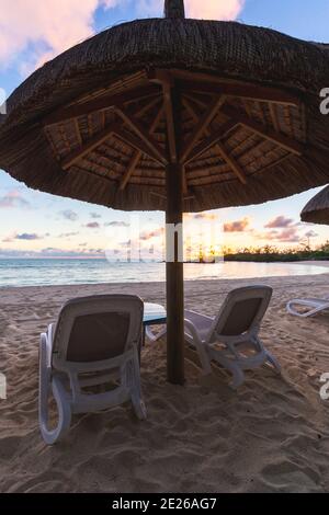 Sonnenaufgang am Strand. Getrocknetes Gras Regenschirme Schatten. Ruhe, Zen, Urlaub, Sommer-Vibes, Entspannung Stimmung auf Stockfoto