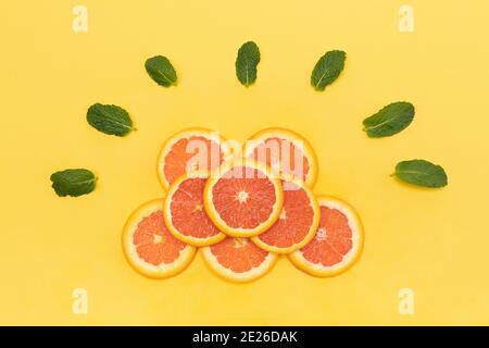 Draufsicht auf geschnittene Grapefruits und Minzblätter auf Gelb Hintergrund Stockfoto