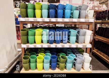 Сups werden im Laden verkauft. Reihen von verschiedenen mehrfarbigen Tassen für zu Hause auf Regalen in einem Supermarkt. Stockfoto