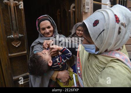 Lahore, Pakistan. Januar 2021. Pakistanische Gesundheitshelferin verabreicht einem Kind während einer Tür-zu-Tür-Kampagne zur Polio-Impfung einen Polio-Impfstoff. Trotz eines stetigen Anstiegs der Coronavirus-Fälle startete Pakistan am Montag eine fünftägige Impfkampagne gegen Polio inmitten strenger Sicherheit, in der Hoffnung, die lähmende Kinderkrankheit in diesem Jahr auszurotten. (Foto von Rana Sajid Hussain/Pacific Press/Sipa USA) Quelle: SIPA USA/Alamy Live News Stockfoto