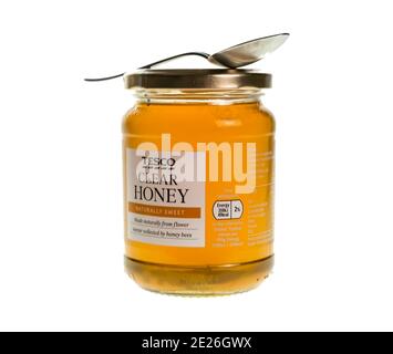 Norwich, Norfolk, Großbritannien – Dezember 20 2020. Ein illustratives Foto von einem Glas Tesco gebrandeten Honig, zusammen mit einem Teelöffel, Stockfoto