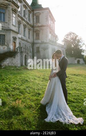 Schöne Braut und Bräutigam stehen vor dem alten Schloss. Hochzeitspaar. Hochzeitsfoto Stockfoto