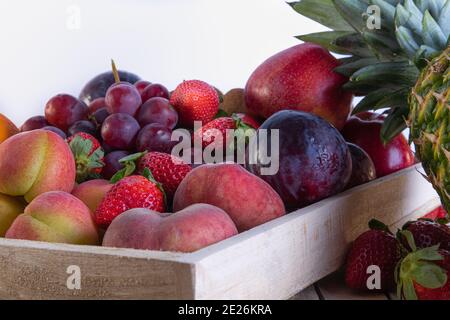 Nahaufnahme von reifen Früchten und Beeren in einer Holzkiste Isoliert auf weißem Hintergrund Stockfoto