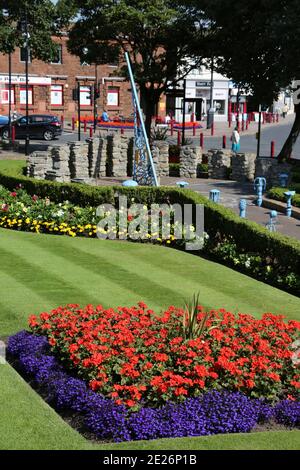 Prestwick Cross, Prestwick, Ayrshire, Schottland. VEREINIGTES KÖNIGREICH. Die ungewöhnliche Sonnenuhr zeigt von 4 bis 20 Uhr in Stunden. Stundenmarkierungen sind auf Steinsäulen mit Motiven, die lokale Interessen bezeichnen. Großer durchbohrter Gnomon mit aufwendigen Sonne, Mond, Sternen und Tierkreiszeichen. Die Platte ist von concre &tiles und bildet eine grobe Karte des Firth von Clyde, mit der Insel von Arran und einigen Straßen auf dem Festland. Die Sonnenuhr wurde von Kunststudenten des 6. Jahrgangs der Prestwick Academy mit Unterstützung von Mitgliedern der Kunstabteilung konzipiert und gestaltet, die in Zusammenarbeit mit der Künstlerin Elspeth Bennie aus Balfron arbeiteten. Stockfoto