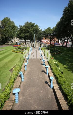 Prestwick Cross, Prestwick, Ayrshire, Schottland. VEREINIGTES KÖNIGREICH. Die ungewöhnliche Sonnenuhr zeigt von 4 bis 20 Uhr in Stunden. Stundenmarkierungen sind auf Steinsäulen mit Motiven, die lokale Interessen bezeichnen. Großer durchbohrter Gnomon mit aufwendigen Sonne, Mond, Sternen und Tierkreiszeichen. Die Platte ist von concre &tiles und bildet eine grobe Karte des Firth von Clyde, mit der Insel von Arran und einigen Straßen auf dem Festland. Die Sonnenuhr wurde von Kunststudenten des 6. Jahrgangs der Prestwick Academy mit Unterstützung von Mitgliedern der Kunstabteilung konzipiert und gestaltet, die in Zusammenarbeit mit der Künstlerin Elspeth Bennie aus Balfron arbeiteten. Stockfoto