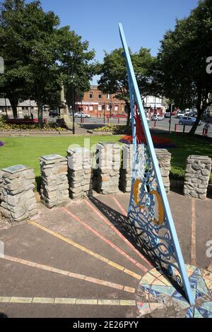 Prestwick Cross, Prestwick, Ayrshire, Schottland. VEREINIGTES KÖNIGREICH. Die ungewöhnliche Sonnenuhr zeigt von 4 bis 20 Uhr in Stunden. Stundenmarkierungen sind auf Steinsäulen mit Motiven, die lokale Interessen bezeichnen. Großer durchbohrter Gnomon mit aufwendigen Sonne, Mond, Sternen und Tierkreiszeichen. Die Platte ist von concre &tiles und bildet eine grobe Karte des Firth von Clyde, mit der Insel von Arran und einigen Straßen auf dem Festland. Die Sonnenuhr wurde von Kunststudenten des 6. Jahrgangs der Prestwick Academy mit Unterstützung von Mitgliedern der Kunstabteilung konzipiert und gestaltet, die in Zusammenarbeit mit der Künstlerin Elspeth Bennie aus Balfron arbeiteten. Stockfoto