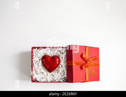 Rotes Herz zwischen crinkle geschnittenes Papier in Geschenkbox auf weißem Hintergrund. Valentinskarte mit Kopierplatz, Draufsicht Stockfoto
