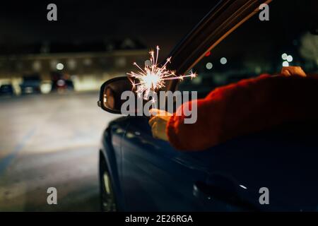 Unverkennbare Frau im Auto mit einem Wunderkerzen in der Nacht Stockfoto