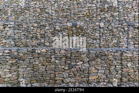 Metallkäfige gefüllt mit Steinen. Gabionen Schutzwand mit Steinen gefüllt und mit dickem Metalldraht gebunden. Gabion Hintergrundmuster Stockfoto