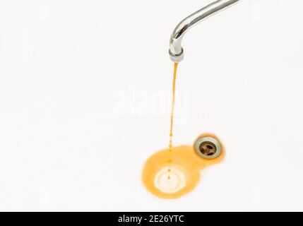 Rostiges oder schmutziges Wasser fließt aus einem Wasserhahn in ein Waschbecken oder eine Badewanne. Stockfoto