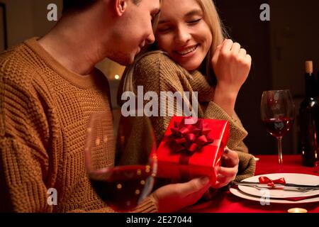 Liebevoller Mann geben rote Geschenkbox Umarmung geliebte Frau oder Valentinstag. Stockfoto