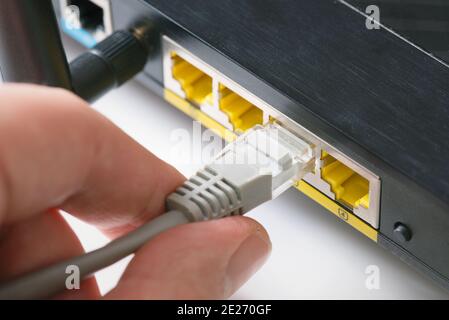 WLAN-Nahaufnahme des Routers. Schnelles Internet-Modem-Gerät. Man steckt das ethernet-Kabel in die Buchse Stockfoto