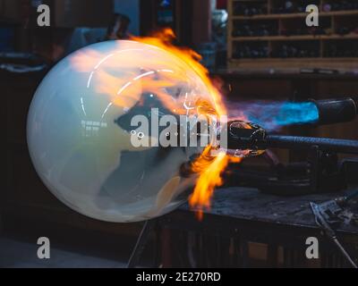 Handwerkliche Hände arbeiten mit heißem formbarem Glas und heizen es mit Gasbrenner. Nahaufnahme der Methode des Künstlers. Tschechische handgemachte Glas Studio. Stockfoto