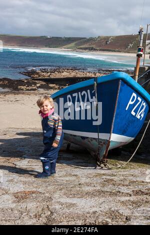 Kleiner Junge und ein Fischerboot auf der Slipway in Sennen Cove, Penwith Peninsula, Cornwall, Großbritannien. MODELL FREIGEGEBEN Stockfoto