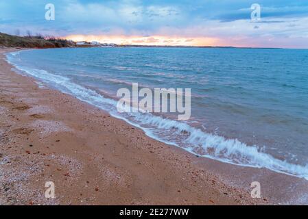 Meereswellen Hintergrund mit Sand und Schaum bei Sonnenuntergang. Stockfoto