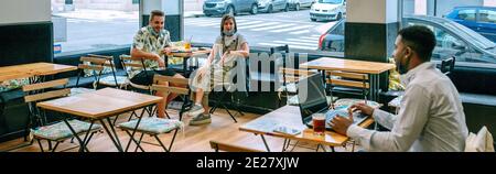 Junger Mann Telearbeit im Café im Gespräch mit Freunden pflegen Stockfoto