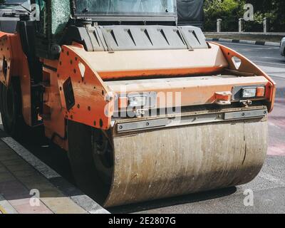 Die Straßenwalze steht in der Nähe der Bordsteinkante auf der Straße. Straßendienst. Stockfoto