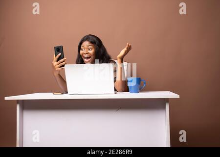 Eine junge Dame, die ihr Telefon in ihrem Büro benutzt Stockfoto