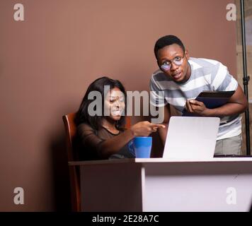 Eine Dame und ein junger Mann betrachten einen Laptop Stockfoto