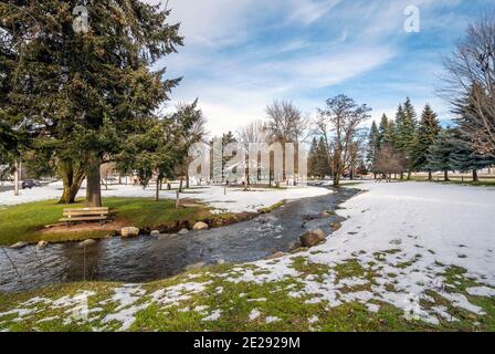 Ein kleiner Bach fließt durch den kleinen öffentlichen Park mit Schnee im Winter bei Rathdrum, Idaho USA. Stockfoto