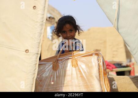 (210112) -- HAJJAH (JEMEN), 12. Januar 2021 (Xinhua) -- EIN vertriebenes Kind trägt eine Tüte Decke, nachdem es sie von einer Wohltätigkeitsgruppe in der Provinz Hajjah im nördlichen Jemen am 12. Januar 2021 erhalten hatte. Die globalen Kosten der internen Vertreibung hat 20 Milliarden US-Dollar pro Jahr erreicht, im Vergleich zu 13 Milliarden Dollar vor zwei Jahren, sagte das Internal Displacement Monitoring Center (IDMC) am Dienstag. Der Anstieg wird durch einen Anstieg der Zahl der Menschen in Binnenvertriebenen erklärt, die bis Ende 2019 ihren Höhepunkt erreicht hatten und jetzt weltweit bei 51 Millionen liegt, sagte die IDMC in einem Bericht veröffentlicht Tuesda Stockfoto