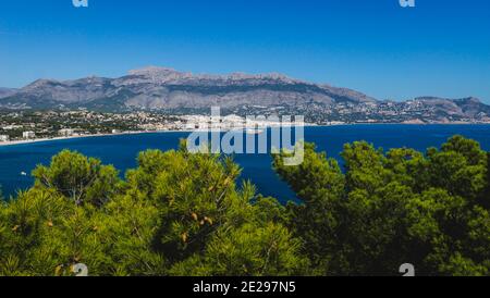 Panoramablick auf die Küste von Atea über das Mittelmeer und verschwommene Kiefern im Naturpark 'Serra Gelada' in Albir, Costa Blanca, Spanien Stockfoto