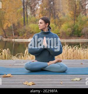 Junge hübsche Frau tut Yoga Posen im Park Herbst. Hochwertige Fotos Stockfoto