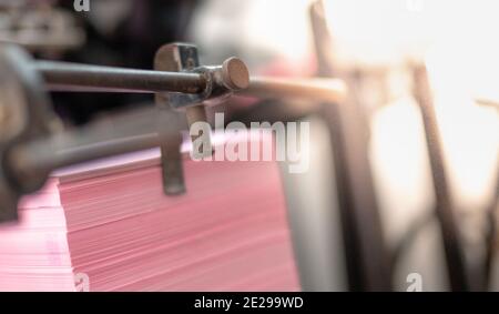 Die bedruckten Papierbögen werden in der alten Buchdruckmaschine mit dem rostigen, kleinen Druckindustriekonzept serviert. Stockfoto
