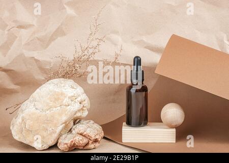 Braune Glasflaschen von kosmetischen Produkten auf Stein und hölzernen geometrischen Formen auf beige Handwerk Papier Hintergrund. Natürliche organische Spa kosmetische Schönheit con Stockfoto