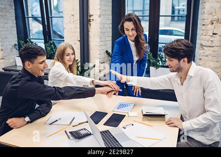 Geschäftsleute, die ihre Hände im Büro zusammenlegen Stockfoto