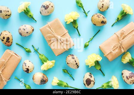 Frühlingsblumen und Eier Hintergrund oder Tapete. Gelbe Blumen, Bastelgeschenke und Wachteleier auf blauem Hintergrund. Happy Easter, Zero Waste Konzept Kreativ Stockfoto