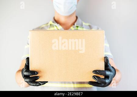 Delivery Service Mann in Schutzhandschuhe und Maske halten Karton-Box. Lieferservice, Online-Shopping und Logistikkonzept. Sichere Lieferung. Stockfoto