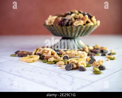 Rustikale Metall angehoben Gericht mit gesunden Trail-Mischung mit Erdnüssen, Walnüssen, Müsli, getrocknete Cranberry, Schokolade Chips, Bananenchips gefüllt, sitzen Stockfoto