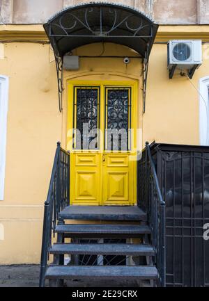 Alte Holztür in leuchtendgelber Farbe in einer Innenstadt. Stockfoto