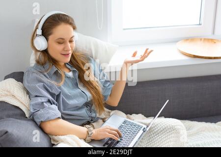 Kaukasische Frau während eines Online-Gesprächs. Sie hat einen Videoanruf, während sie zu Hause auf der Couch sitzt. Modernes Technologiekonzept. Selektiver Fokus. Stockfoto