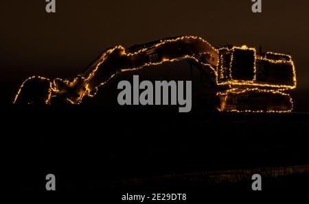 Umea, Norrland Schweden - 27. Dezember 2020: Beleuchteter Bagger mit Lichtschleifen Stockfoto