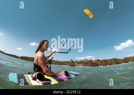 Sportlicher Kite Surfer steht im Wasser mit Wakeboard Stockfoto