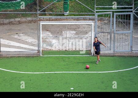 MEDELLIN, KOLUMBIEN - 23. Dezember 2020: Medellin, Kolumbien - 23 2020. Dezember: Eine junge hispanische Frau praktiziert und spielt Fußball auf einem öffentlichen Feld mit GRE Stockfoto