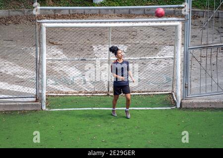 MEDELLIN, KOLUMBIEN - 23. Dezember 2020: Medellin, Kolumbien - 23 2020. Dezember: Eine junge hispanische Frau in schwarzer Sportswear spielt Fußball auf einem öffentlichen Feld wi Stockfoto