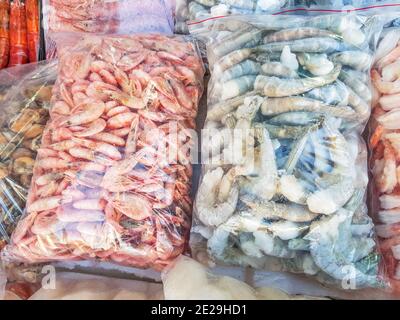 Zwei große Plastiktüten mit gefrorenen rohen und gekochten Garnelen, auf der Theke des Fischmarktes. Stockfoto