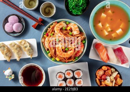 Japanische Küche. Sushi, udon, Miso-Suppe, Tee, Mochi usw., von oben auf blauem Hintergrund aufgenommen Stockfoto