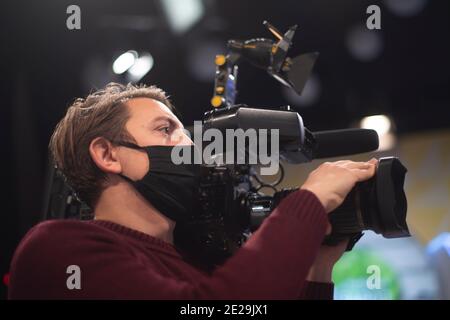 Maskierter Kameramann dreht eine Fernsehshow im Studio. TV Stockfoto