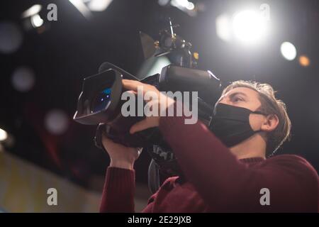 Maskierter Kameramann dreht eine Fernsehshow im Studio. TV Stockfoto