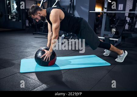 Sportler, der eine Plank mit Medizinball macht Stockfoto