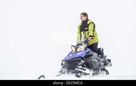 Sportler fährt ein Schneemobil in den Bergen. Schneemobil im Schnee. Konzept Wintersport. Der Mensch fährt Schneemobil in den Bergen. Pilot auf einer Sportart Stockfoto